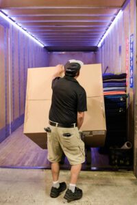 Gasperson mover lifting moving box on a dolly into moving truck