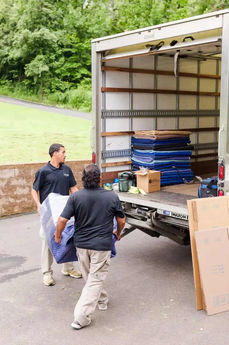 Two movers a large, well-wrapped item onto Gasperson Moving & Storage moving truck
