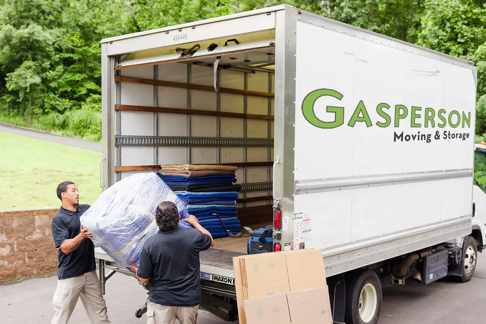 Two Gasperson movers a large, wrapped item into the moving truck