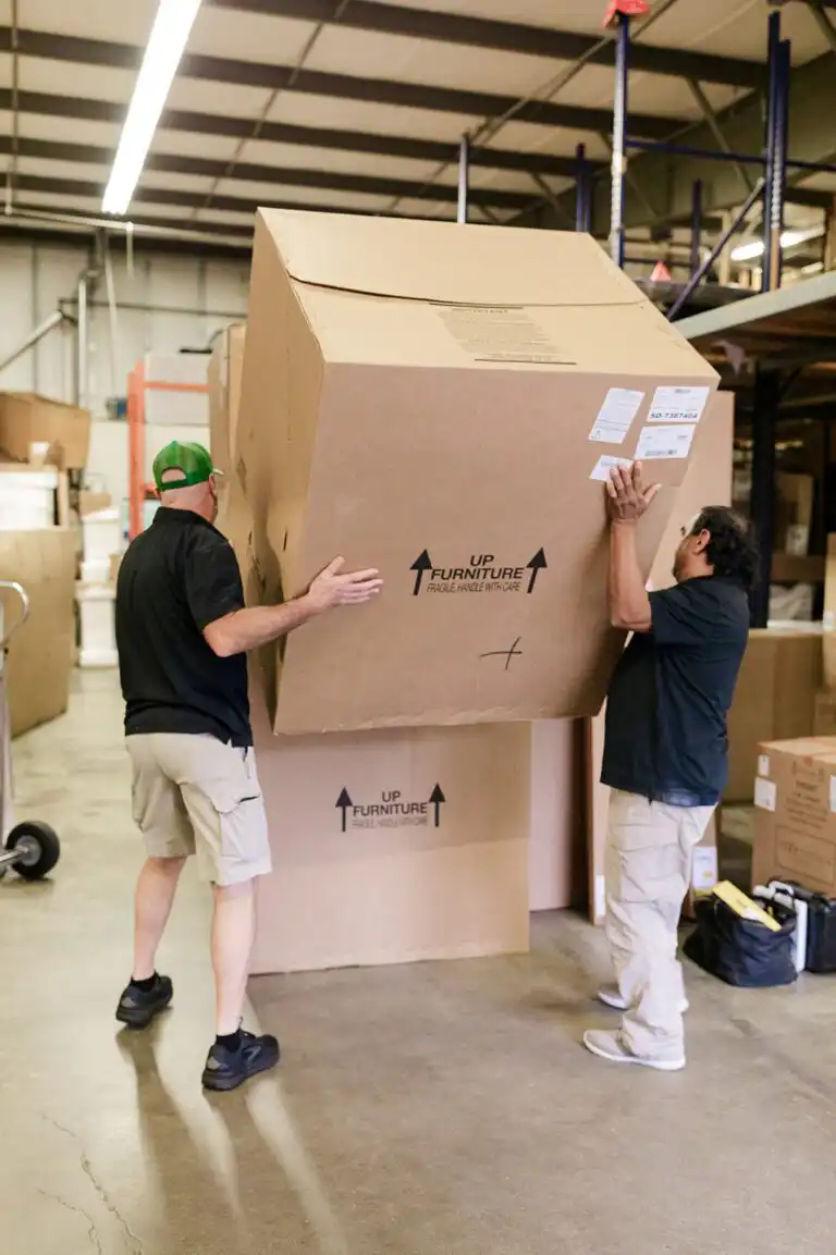 Gasperson movers stacking large moving boxes in warehouse