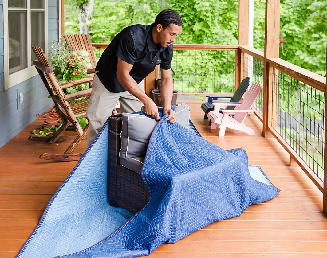 Gasperson mover carefully wrapping up an outdoor chair on a residential patio