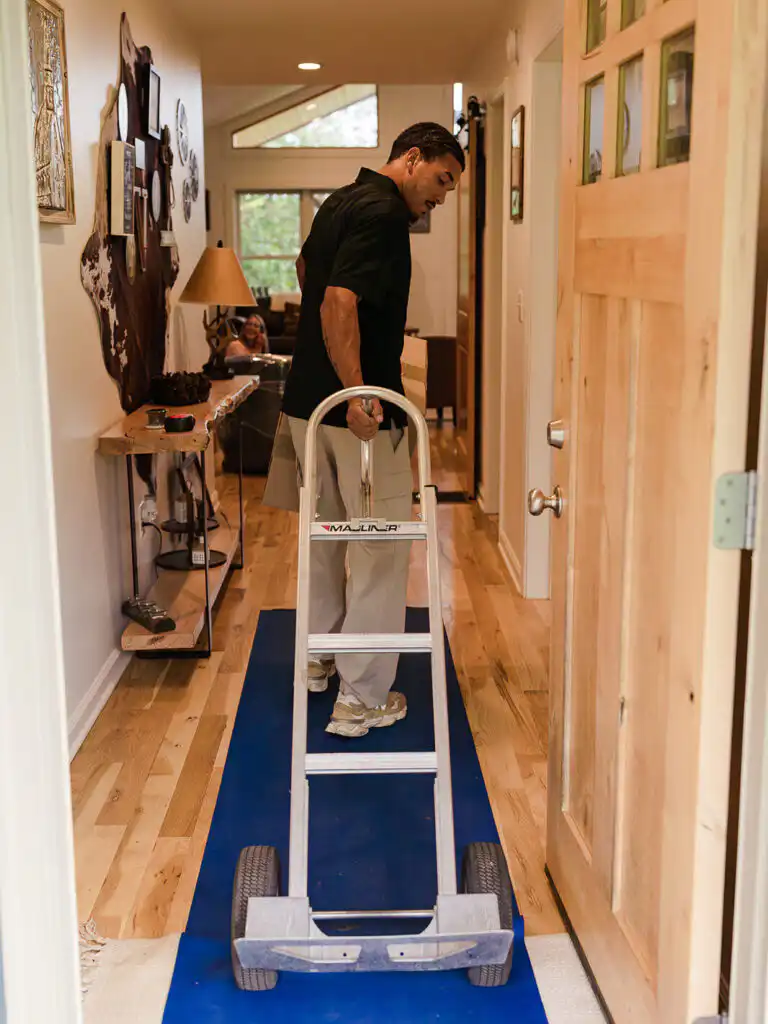 Gasperson mover pulling moving dolly into residential home