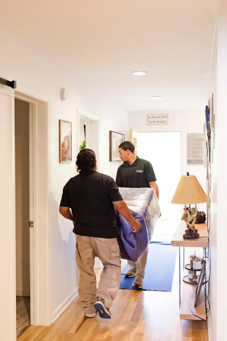 Gasperson movers carefully carrying large item through residential home