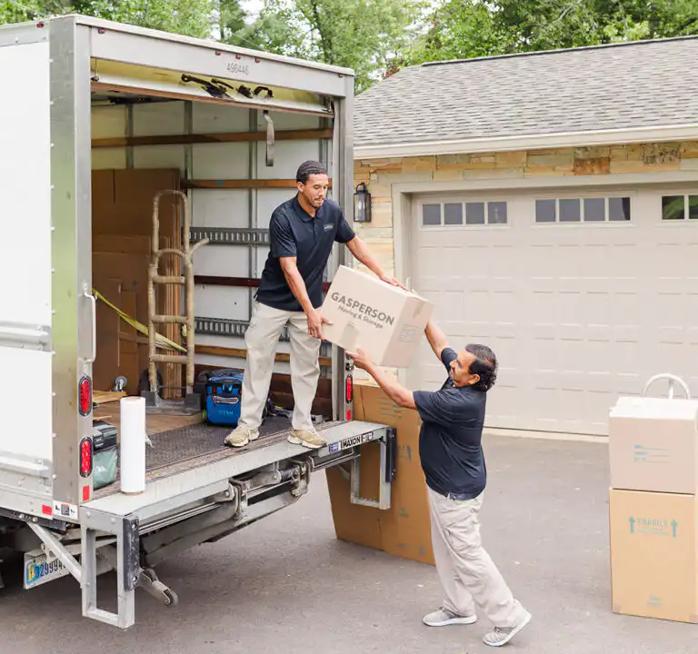 Mover handing moving box to another mover in Gasperson Moving & Storage moving truck