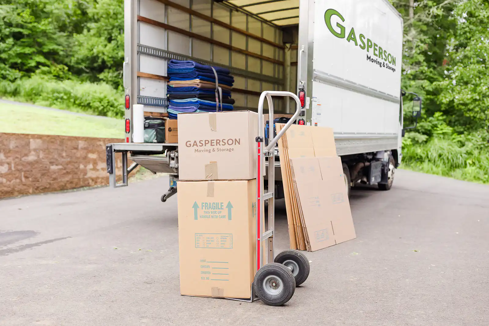 Moving boxes stacked on top of dolly in front of Gasperson Moving & Storage moving truck